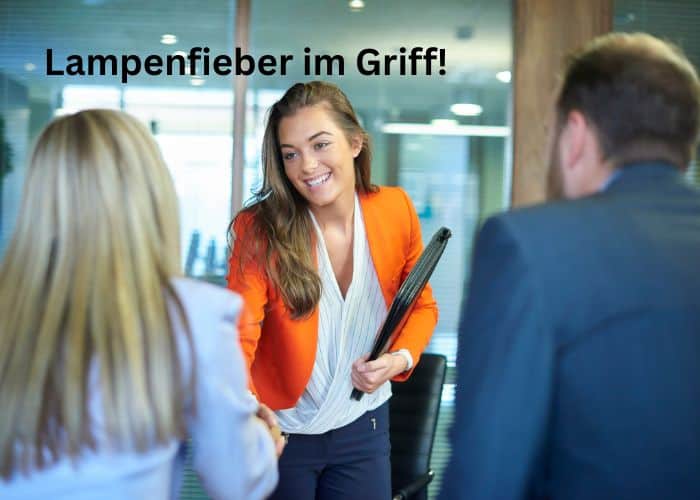 Eine lächelnde Frau in einem leuchtend orangefarbenen Blazer schüttelt jemandem die Hand und hält in ihrem anderen Arm Dokumente. Zwei Personen stehen ihr gegenüber, und oben steht der deutsche Text "Lampenfieber im Griff".