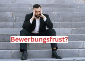Ein Mann im Anzug sitzt auf einer Freitreppe und st&uuml;tzt seinen Kopf gestresst in die H&auml;nde. Das deutsche Wort "Bewerbungsfrust?" (Bewerbungsfrust) steht in fetten roten Buchstaben quer &uuml;ber das Bild geschrieben.