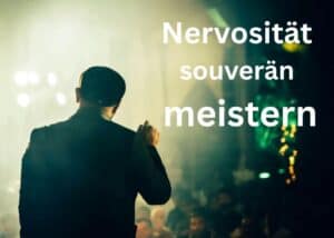 Eine Person im Anzug steht mit einem Mikrofon in der Hand auf der B&uuml;hne und blickt ins Publikum. Der Text auf dem Bild lautet: &bdquo;Nervosit&auml;t souver&auml;n meistern&ldquo;. Der Hintergrund ist unscharf, man erkennt Lichter und Menschen.